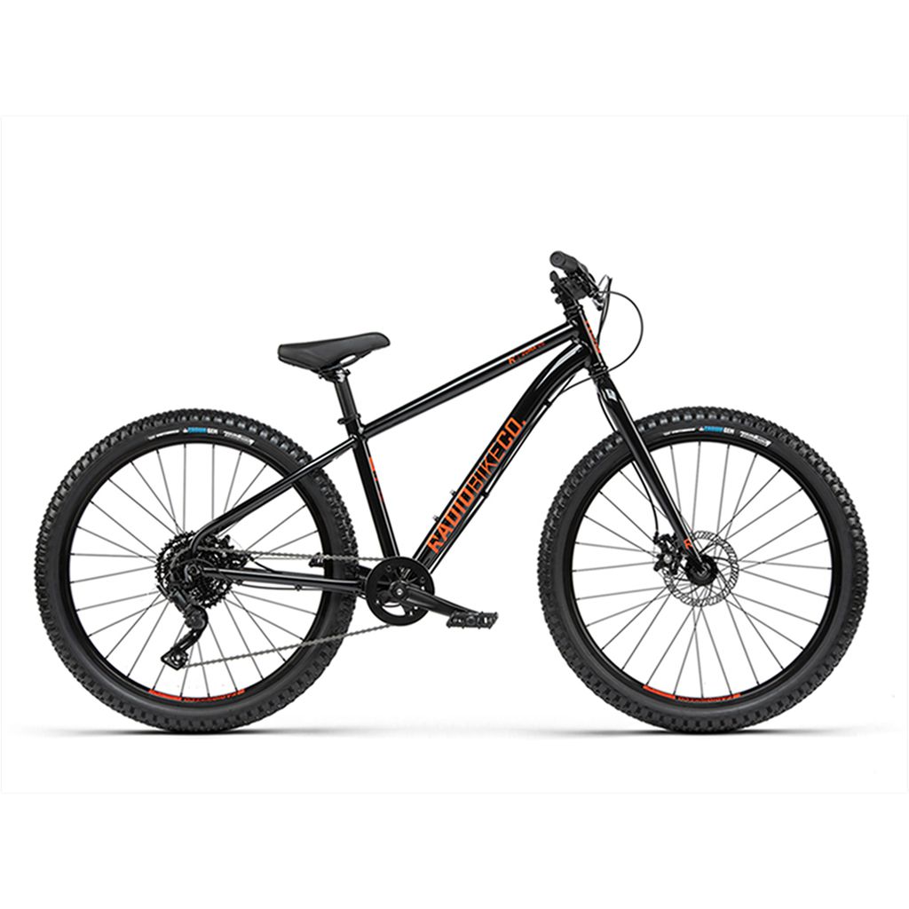 A black mountain bike with orange "Radio 26 Inch Zuma Bike" branding on the lightweight alloy frame, featuring thick tires, a front suspension fork, and disc brakes. The bike is shown on a white background.
