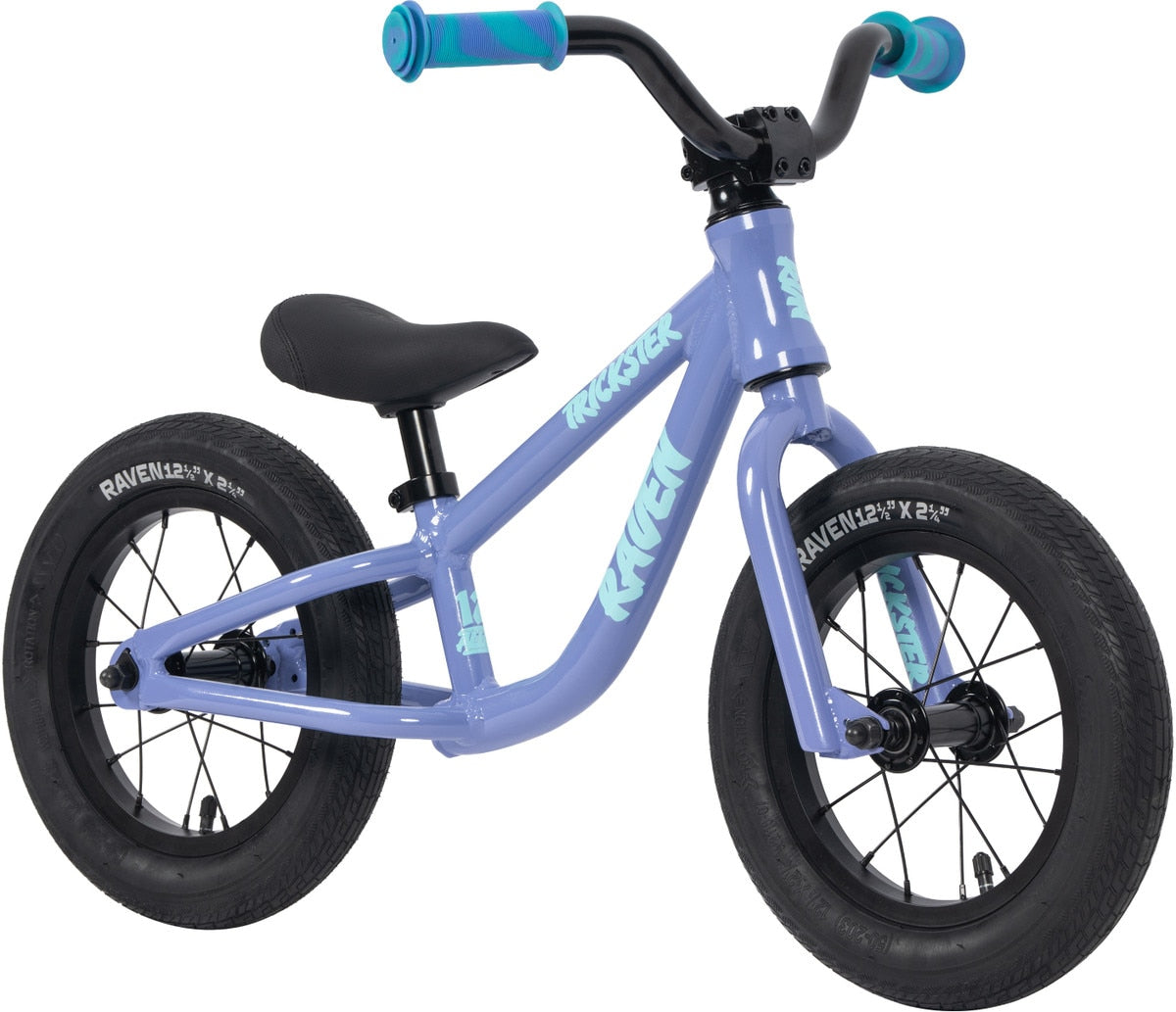 The Raven Trickster Alloy 12 Inch Balance Bike features a lightweight purple alloy frame, black tires, turquoise handlebar grips, and "RAVEN" displayed on the side.
