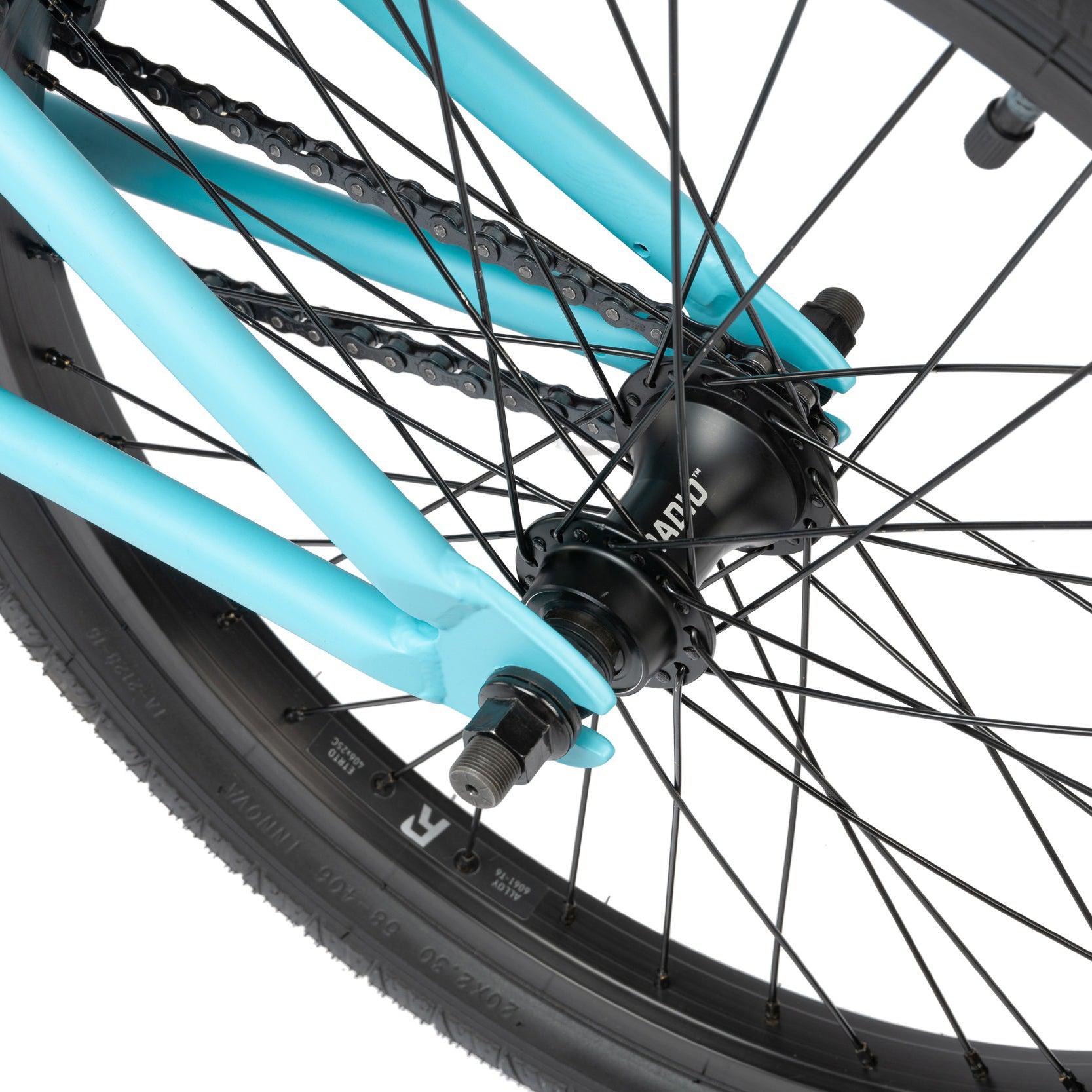 Close-up of a Radio Evol 20 Inch Bike’s rear wheel and hub assembly, showcasing black spokes, a turquoise frame, and a black tire—perfect for beginner riders seeking high-quality bike parts.