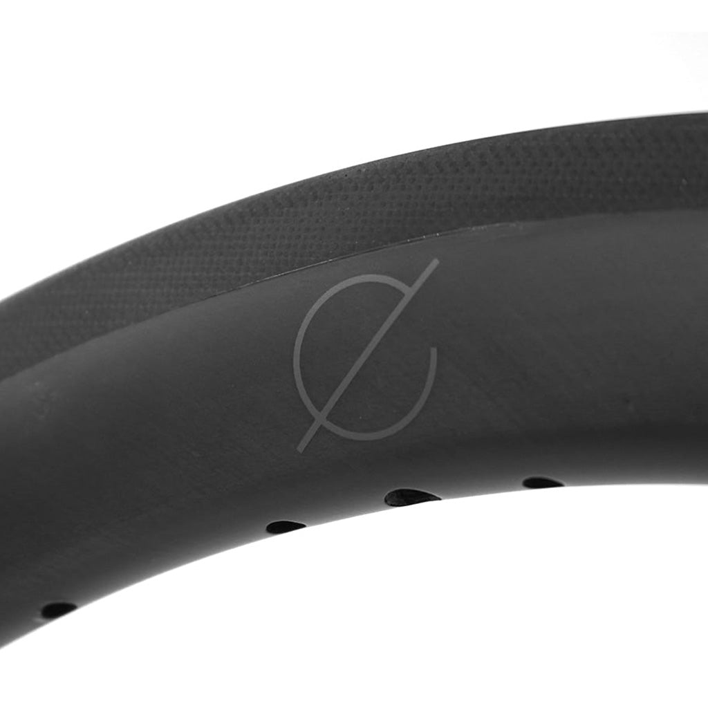 A close up image of a black Spectre Carbon Fibre 451x23mm Braking Rim bicycle tire, emphasizing its reliability and warranty.
