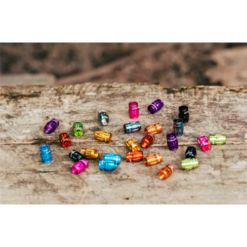 Colorful metal beads scattered on a wooden surface, reminiscent of the vibrant Granite Juicy Valve Caps w/ Valve Tool (Pair) in a tubeless setup, each shining amidst the grainy backdrop.