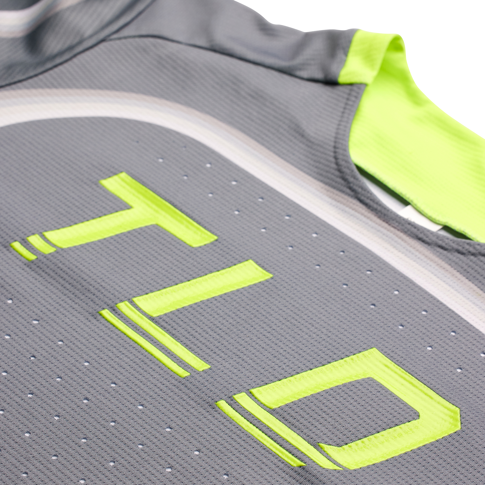 Close-up of a gray TLD Youth Sprint Jersey Reverb Charcoal athletic jersey with neon yellow accents and reflective strips.