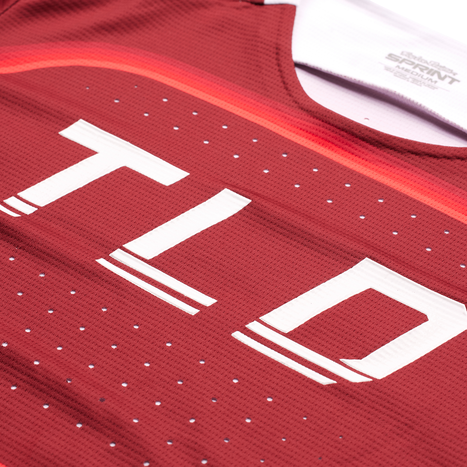 A red TLD Sprint Jersey Reverb BMX race jersey with the word "tld" on it, featuring enhanced ventilation.