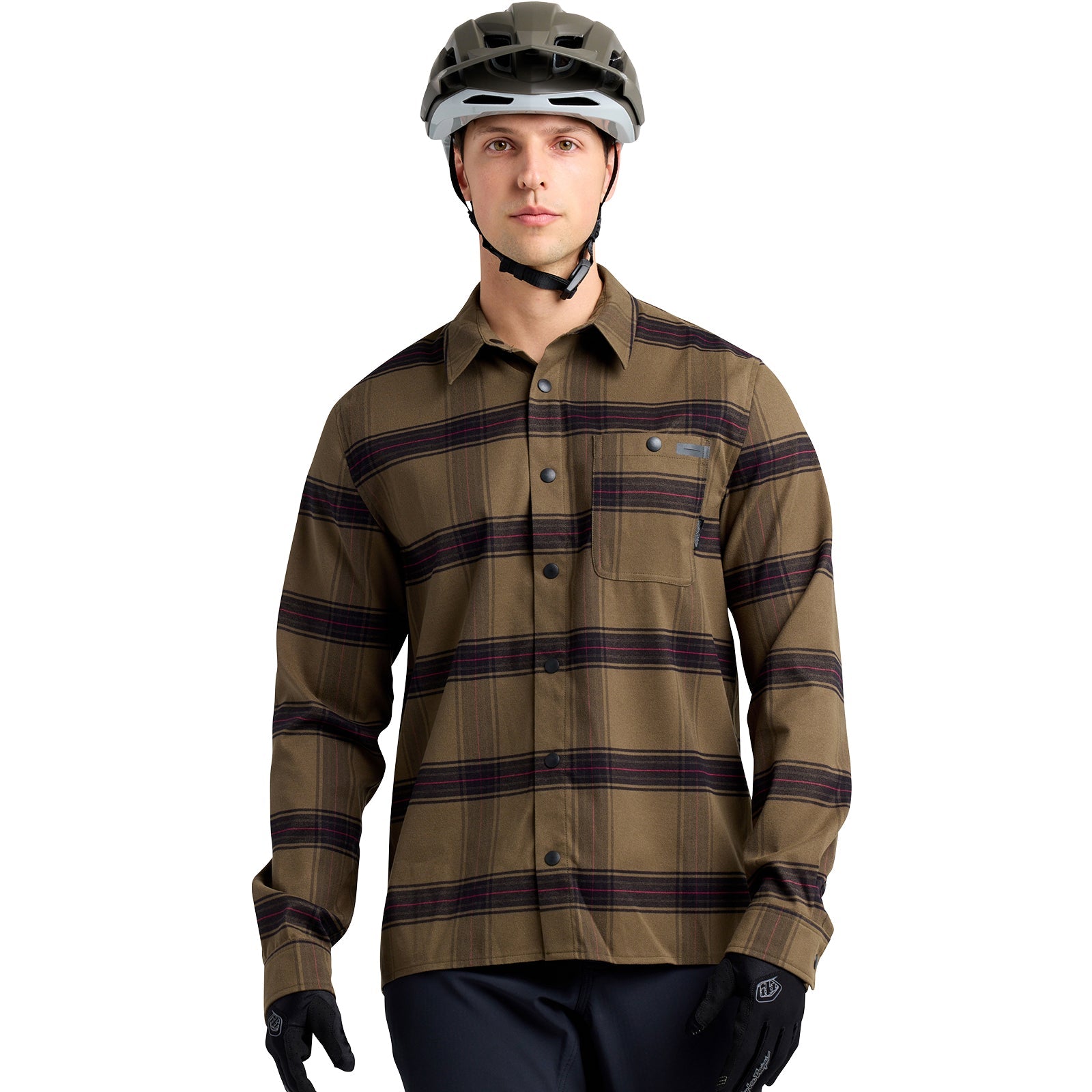 A person wearing a TLD 24.2 Grind Flannel Shirt in brown tech-plaid, black gloves, a bike helmet, and dark breathable performance pants stands against a white background.