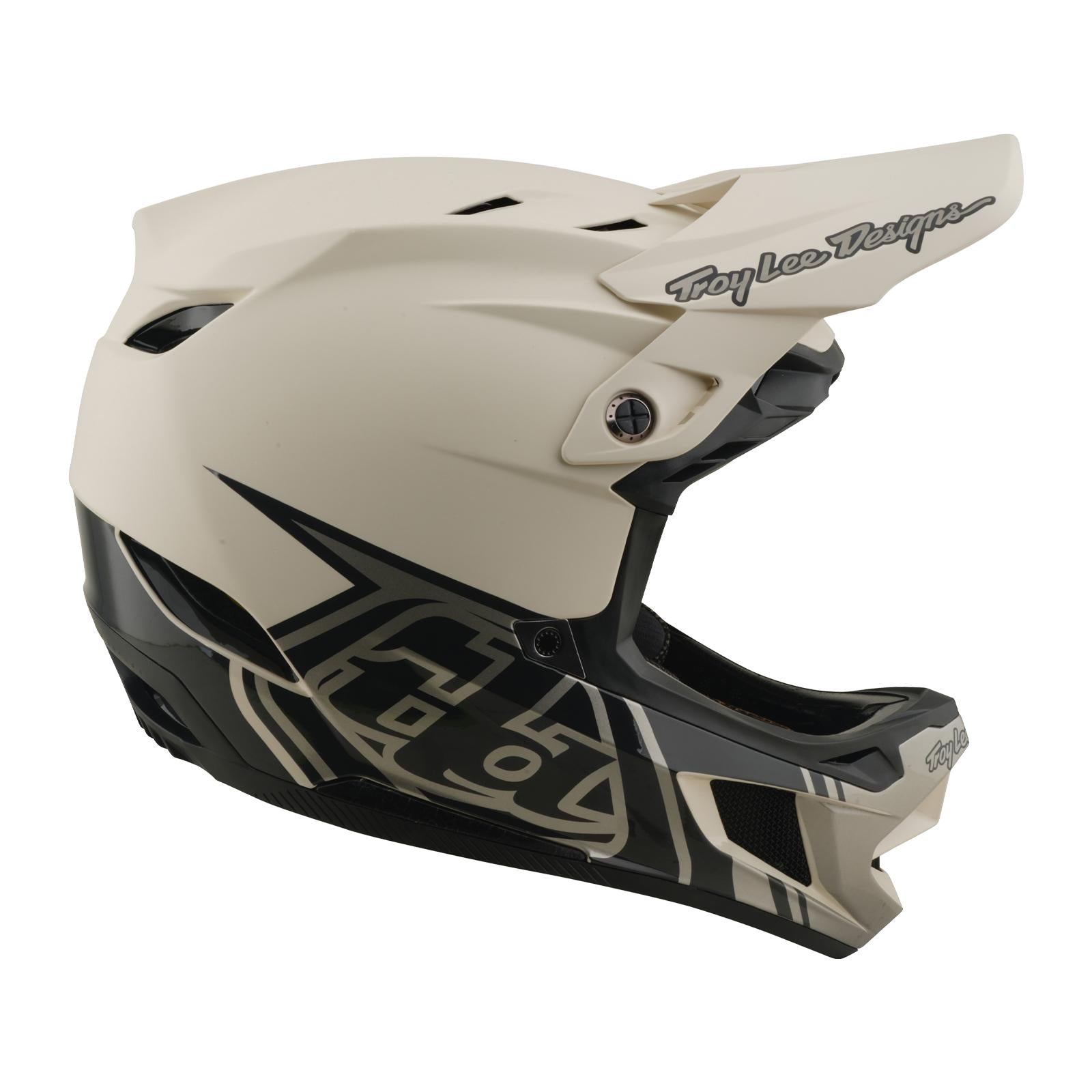 The TLD 26.1 D4 AS Composite Helmet / Stealth Pumice is a beige and black full-face motocross helmet with a visor, Mips protection system, and "Troy Lee Designs" logo on the front.
