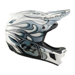 The TLD 26.1 D4 AS Composite Helmet in Torched White/Silver features abstract flame graphics, "Troy Lee Designs" branding on the visor and chin, integrated Mips protection, and is shown in profile view.