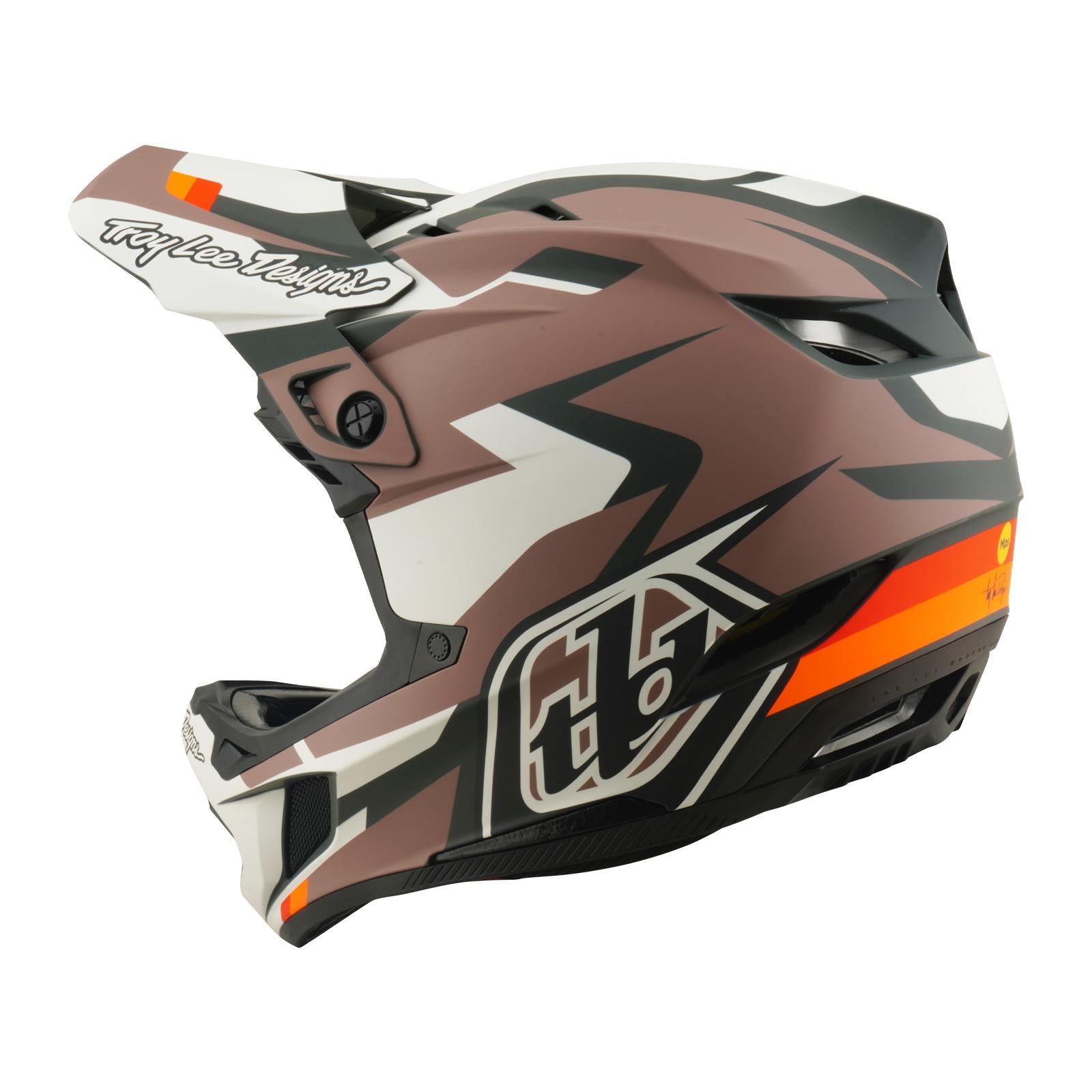 The TLD 26.1 D4 AS Polyacrylite Helmet / Roamer Clay features a brown, black, and white full-face design with zigzag accents, an orange stripe, visor, and Mips brain protection—perfect for motocross or mountain biking, shown in side view.