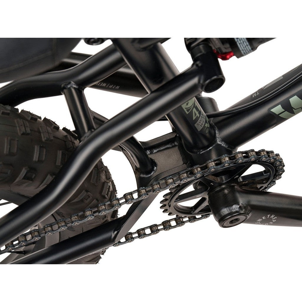 A close up of a black Wethepeople Swampmaster 20 Inch Bike with a chain.