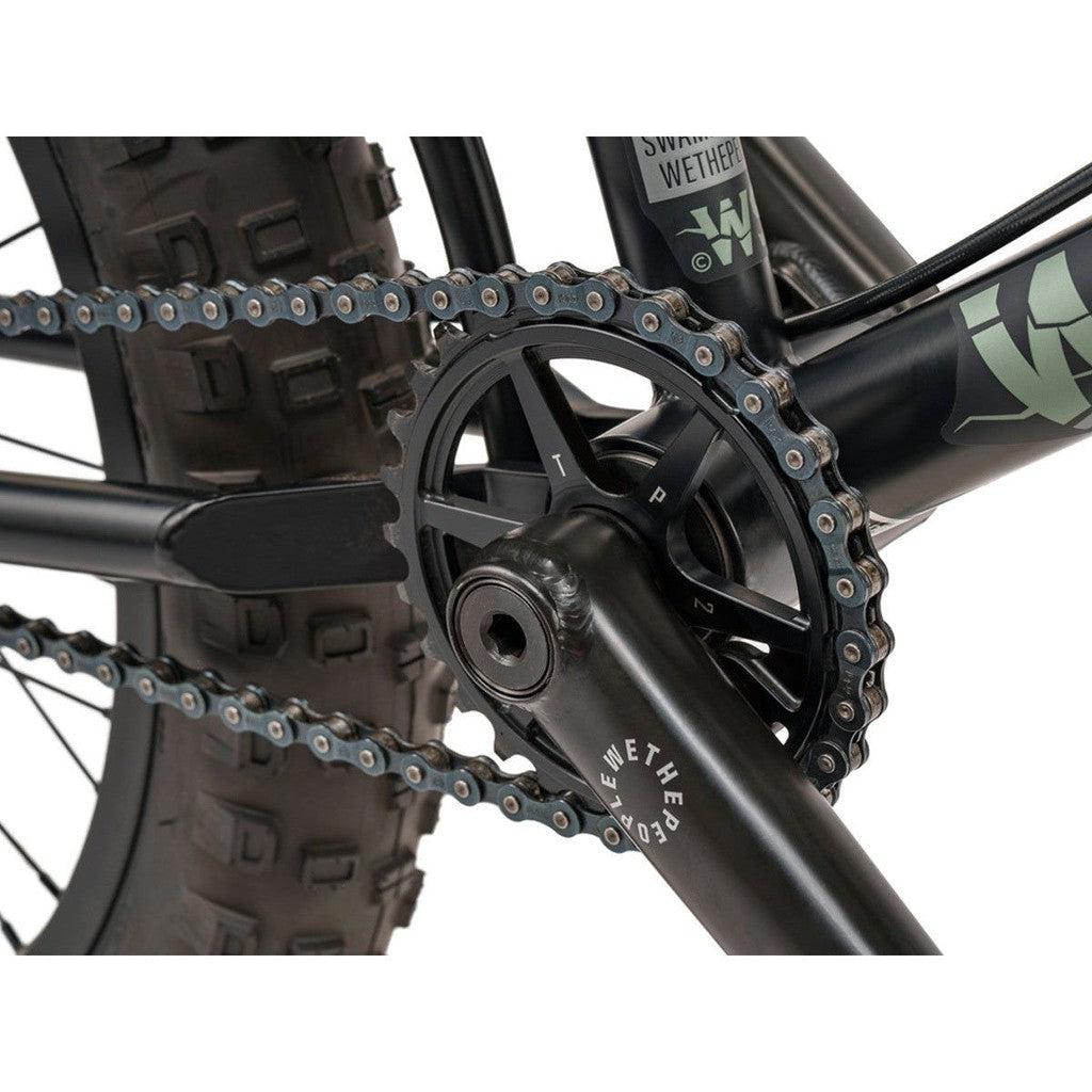 A close up of a black Wethepeople Swampmaster 20 Inch Bike with a chain on it.