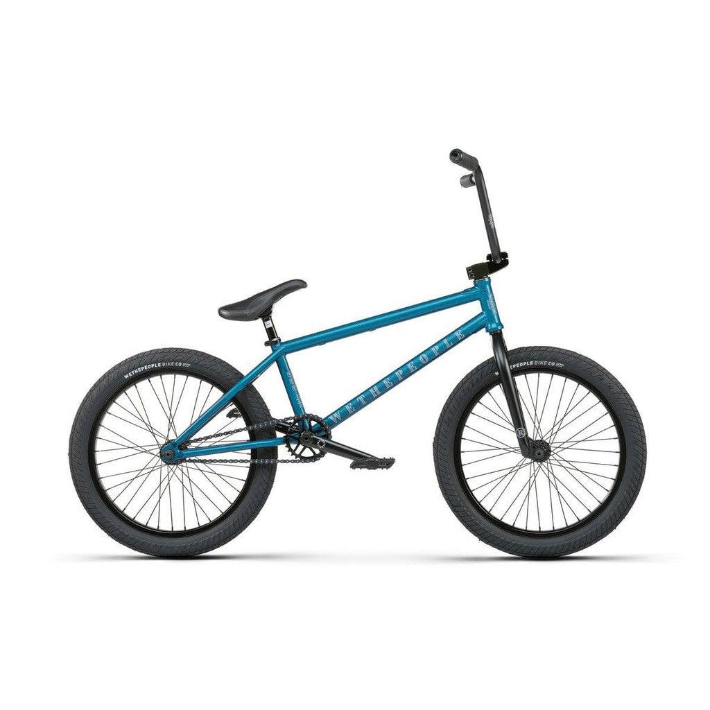 The Wethepeople Revolver 20 Inch Bike in blue features a robust frame with black handlebars and tires, high-end components, and sleek side-view design, making it perfect for tricks and ideal for any Revolver enthusiast.