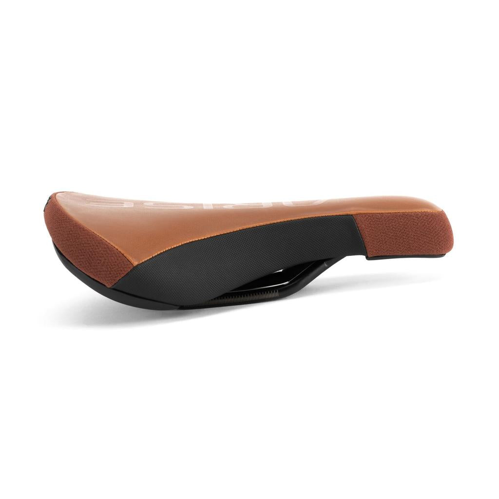 The Arise Sensor Railed Seat, in brown and black with a textured surface and visible rails, is the perfect choice for downhill riding. Set against a white background.