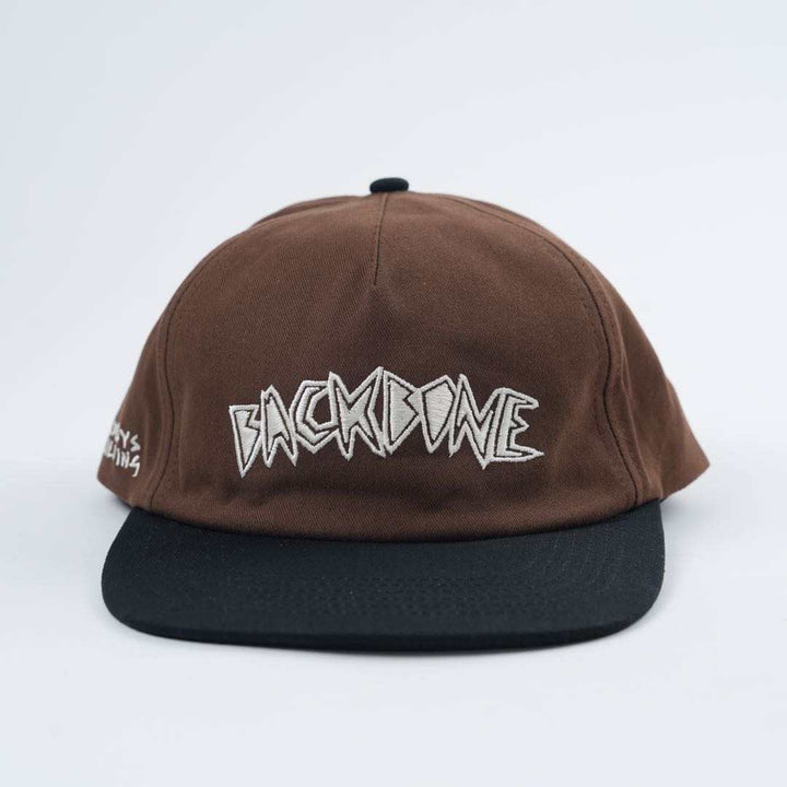 The Backbone Always Building Hat is a brown and black unstructured hat featuring "BACKBONE" embroidered in white on the front, ideal for Backbone BMX enthusiasts.
