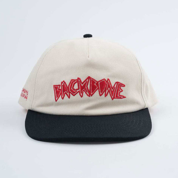 The Backbone Always Building Hat is an unstructured beige and black baseball cap with a bold red, jagged "BACKBONE" embroidered on the front.