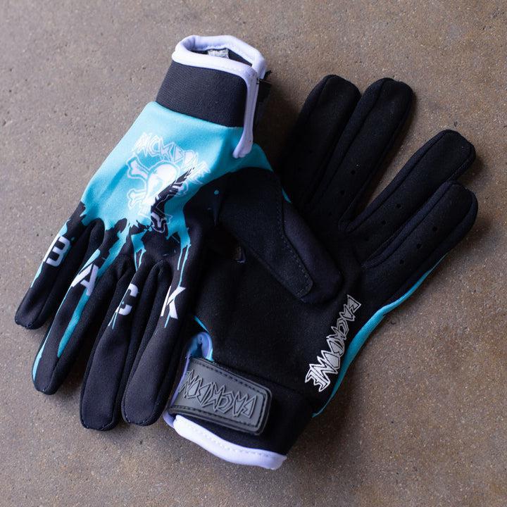The Backbone Gnar Drip Adult Gloves are black and light blue, made with lightweight spandex, featuring a skull design on top, Velcro straps, and "PACHANGA" printed on the wrist.