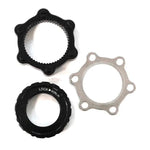 Three mechanical components from the Bengal Centerlock ISO Adapter Kit—a black circular piece with protrusions, a hexagonal ring with internal threads resembling a Centerlock style hub, and a silver circular disc with multiple holes like those found on a 6 bolt ISO disc rotor—laid on a white background.