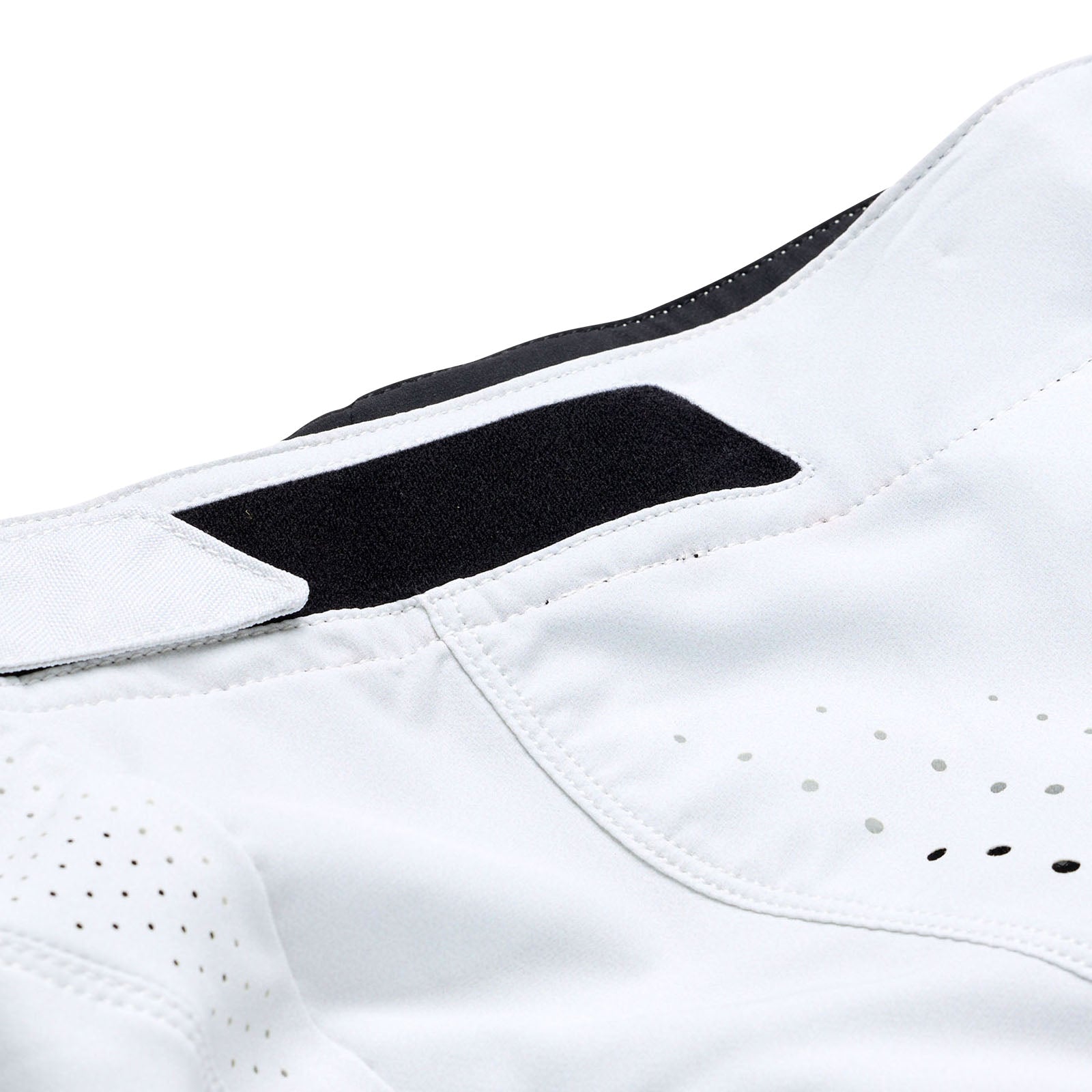 A close-up of a race-ready white garment with a black Velcro strap and perforated details highlights the intricate stitching and fabric texture, reminiscent of the TLD 25.1 Sprint Pant / Mono Chalk design.