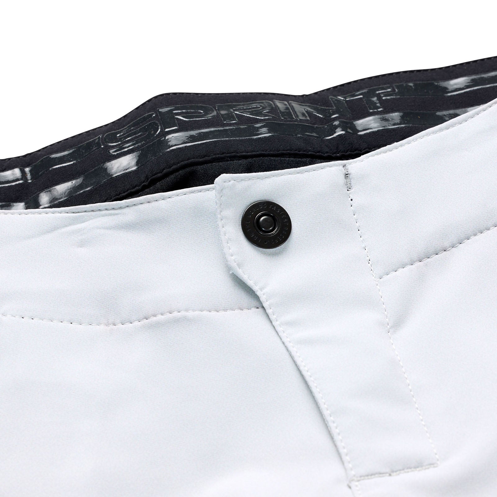 Close-up of the waistband of the TLD 25.1 Sprint Pant / Mono Chalk reveals a black button, belt loops, and inner branding. These light-colored pants are designed for style and performance.