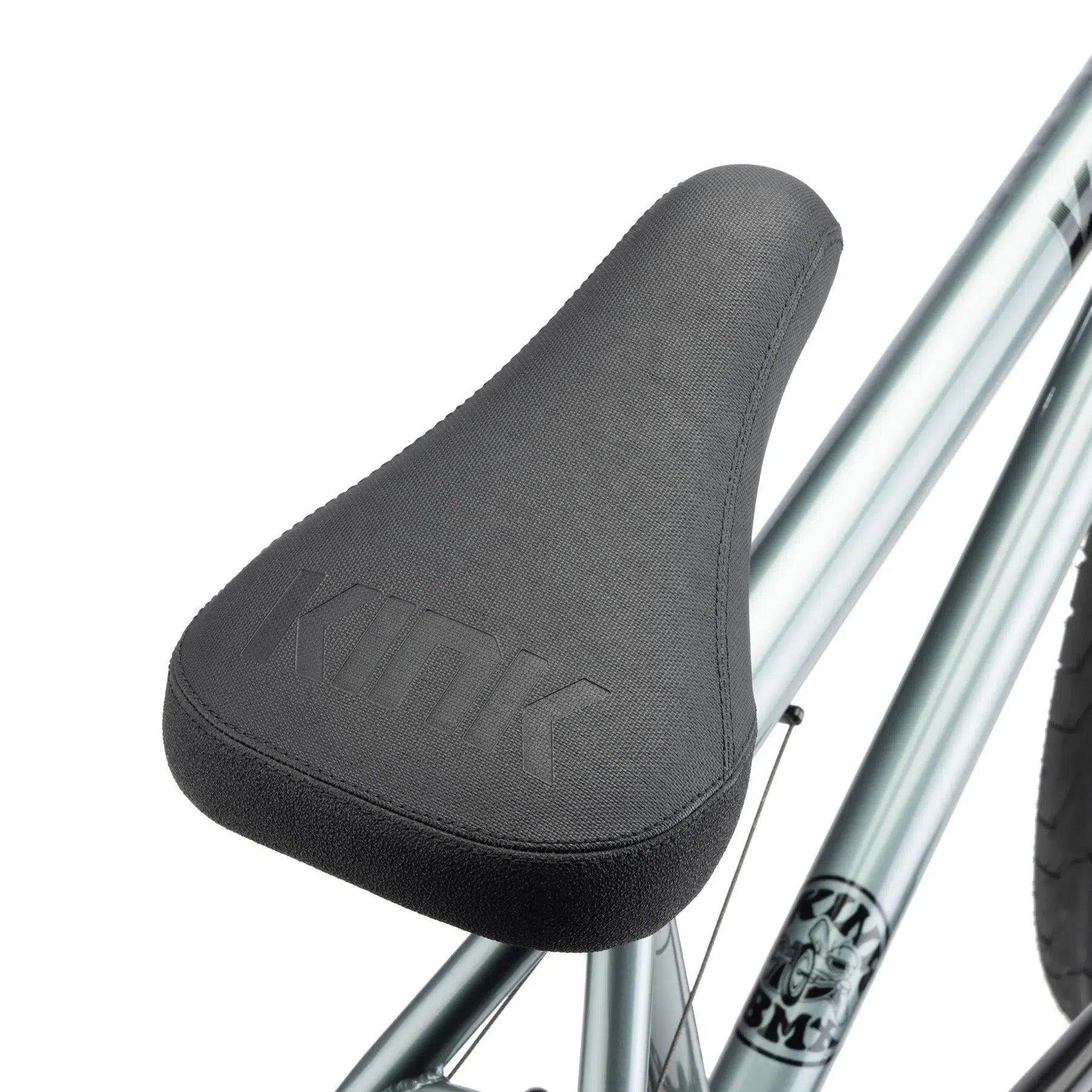 Close-up view of a dark gray BMX bike seat with the word "KINK" embossed on it, attached to a metallic silver Chromoly frame. This sleek design is part of the Kink Whip XL 20 Inch Bike series, built for durability and performance.