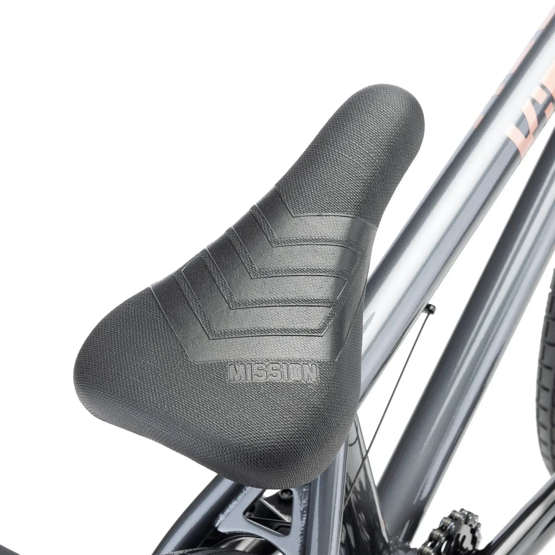 Close-up of a black textured bicycle seat with "MISSION" embossed on it, attached to a metallic grey Kink Kicker 18 Inch Bike (2026)—an ideal kids BMX bike for freestyle adventures.