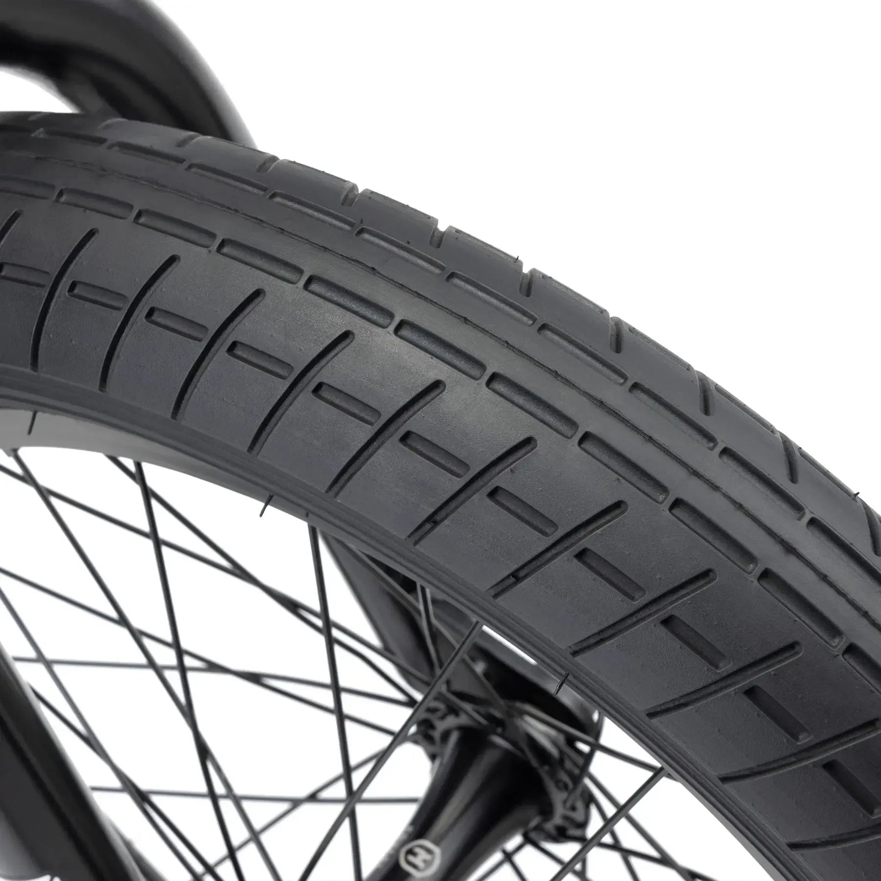 Close-up of a black bicycle tire with a grooved tread, mounted on a wheel—ideal for the Kink Kicker 18 Inch Bike (2026) freestyle BMX or kids' bike.