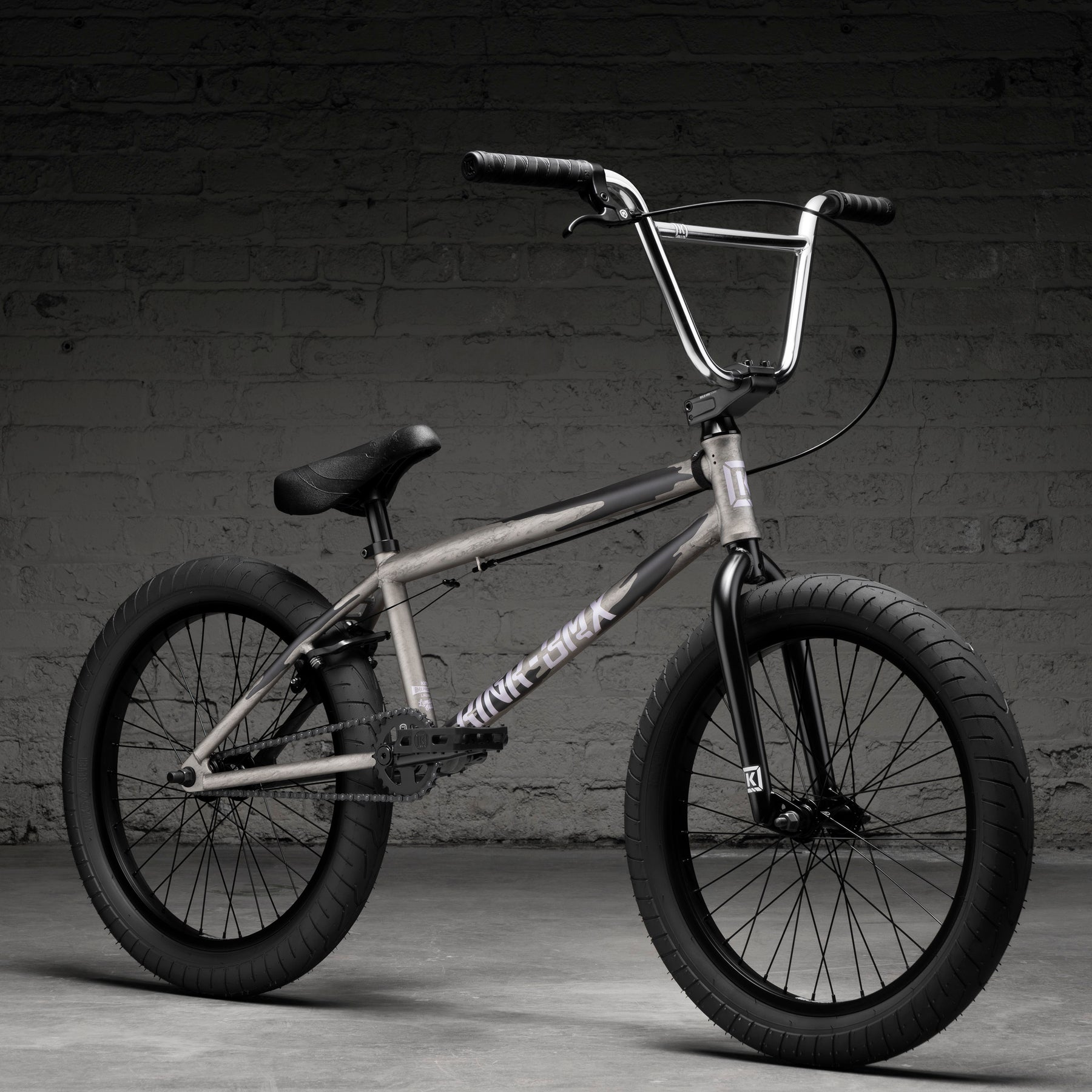 The Kink Launch LTD 20 Inch Bike, a limited edition BMX with a metallic frame, black handlebars, wheels, and seat plus sealed bearing headset, is displayed indoors against a textured brick wall.