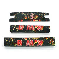 The BMX Crash Pad Set includes three black pads in varying sizes, each featuring bold red "BMX" text and a yellow-green splatter design—perfect for adding stylish protection to your ride.
