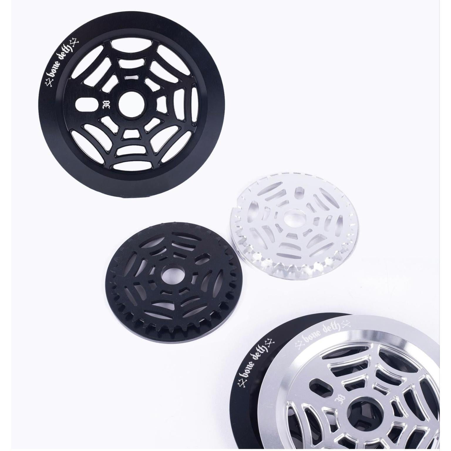 Four BMX sprockets, featuring the Bone Deth Webslinger design, are set against a white background. Each displays unique web-like patterns and vibrant colors, enhancing your ride's style.