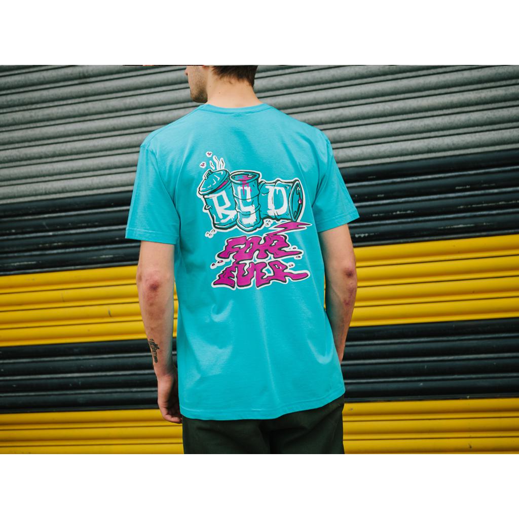 A person in a BSD Spillage T-Shirt, which has a vibrant back screen-print, stands before a corrugated wall with black and yellow stripes.