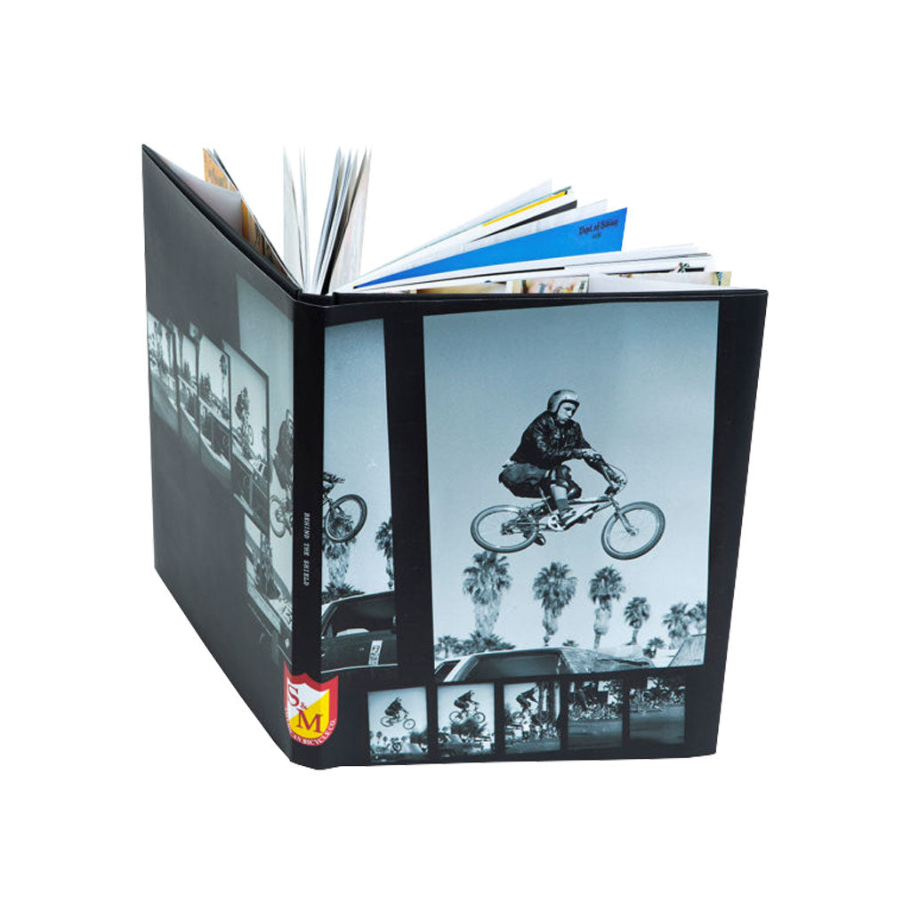 A black and white S&M Behind The Shield Book featuring a person on a BMX bike.