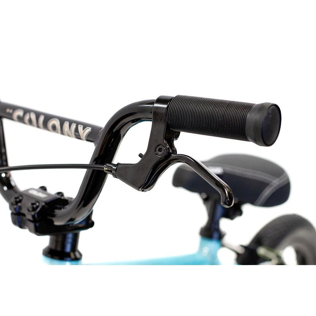 Close-up of the handlebar on the Colony Horizon 12 Inch Bike, featuring a brake lever and grip. The black handlebars contrast with the bike's blue frame, which highlights its lightweight alloy construction, with a black saddle visible in the background.