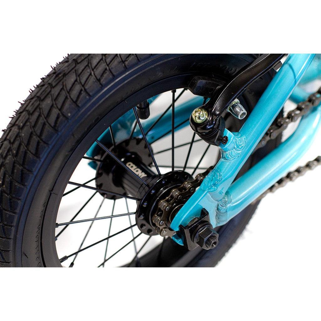 Close-up of the rear wheel and hub of a blue Colony Horizon 12 Inch Bike, showcasing the spokes, tire, and part of its lightweight alloy frame. The design is sleek and built for performance.