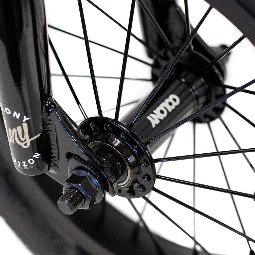 Close-up of a BMX bike wheel, highlighting the spokes, hub, and part of the tire. The name "Colony" is printed on the hub and fork, with the lightweight alloy frame of the Colony Horizon 12 Inch Bike gleaming in view.