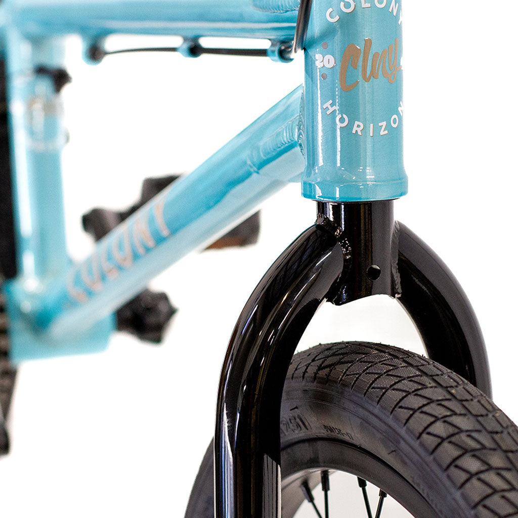 Close-up of a blue Colony Horizon 20 Inch Bike, showcasing its lightweight alloy frame, black front fork, tire, and part of the Colony logo on the head tube.