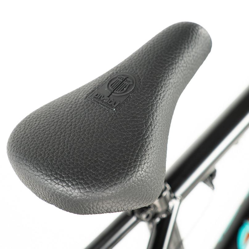 Close-up of a textured black bicycle seat with an embossed logo, attached to the sleek frame of a Colony Sweet Tooth Pro Elite 18 Inch BMX Bike.