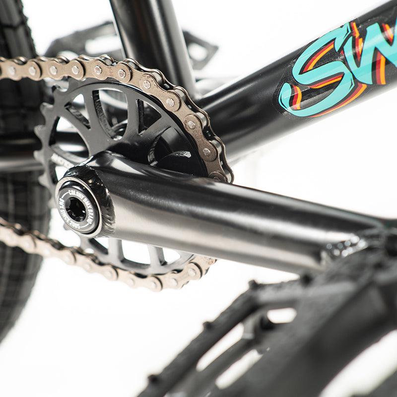 Close-up of a black chainring and pedal crank on the Colony Sweet Tooth Pro Elite 18 Inch BMX Bike, featuring a decorative frame design.