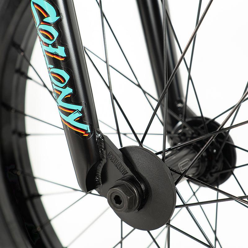 Close-up of a BMX bike wheel highlighting the spokes, hub, and a black fork featuring vibrant "Colony Sweet Tooth Pro Elite 18 Inch" branding.