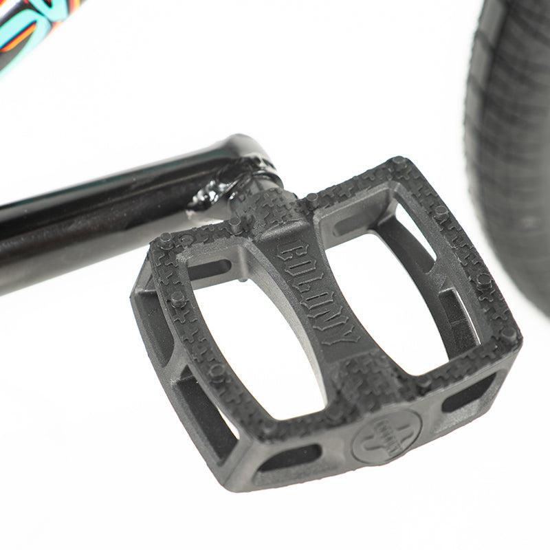 Close-up of a black pedal on a crank arm, with tire tread visible, showcasing the sleek design of the Colony Sweet Tooth Pro Elite 18 Inch BMX Bike.
