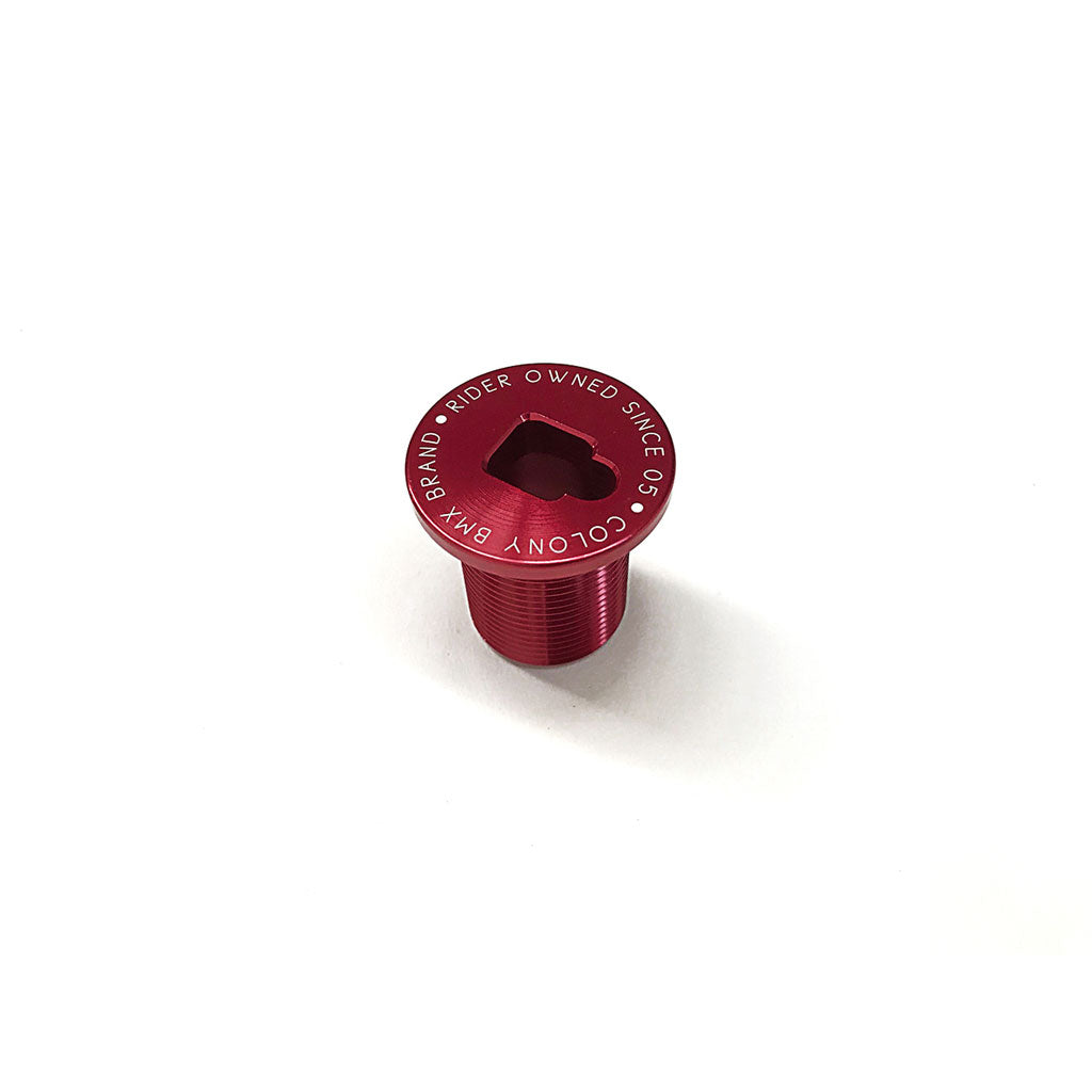 A Colony Fork Pre Load Bolt, in a striking red finish made from durable 7075 T6 Alloy, showcases a hexagonal socket and has "Rider Owned SMC D5" along with "Colony BMX Brand" elegantly inscribed around its edge. It is set against a clean white background, making it an ideal choice for front brakers.