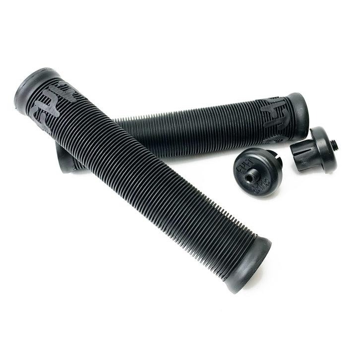 Two Cult Crew Grips in black, featuring a ribbed design with end caps and made from durable rubber, are placed diagonally on a white background.