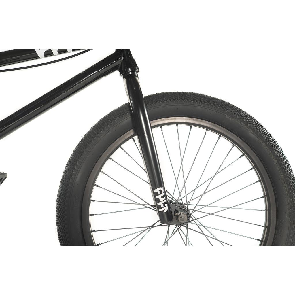 A close-up features the black front wheel of the Cult Access 20 Inch Bike, highlighting its thick tire and metal spokes with the logo on the fork. Its hi-tensile frame is ideal for beginners who want improved maneuverability.