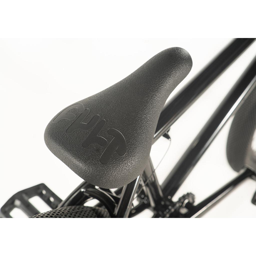 Close-up of a textured black seat with logo, mounted on the Cult Access 20 Inch Bike's shiny black frame—ideal for beginners seeking smooth maneuverability.