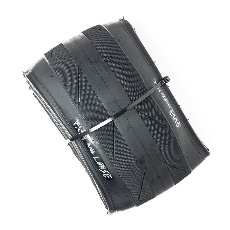 The Cult Fast And Loose Folding Tyre, shown folded and secured with a zip tie, features visible branding and tread designed for low rolling resistance to deliver maximum speed.