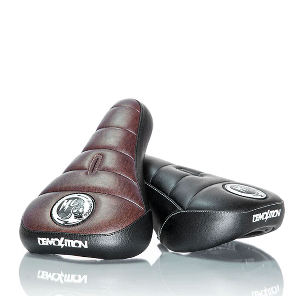 The Demolition Matt Cordova Seat (V1) comes in two stylish colors, brown and black, each adorned with an embroidered logo on the front. Designed with padding and bottom branding, these seats are perfect for BMX enthusiasts. Inspired by Matt Cordova's signature style, they feature the Pivotal Fat Cap system for a secure fit.