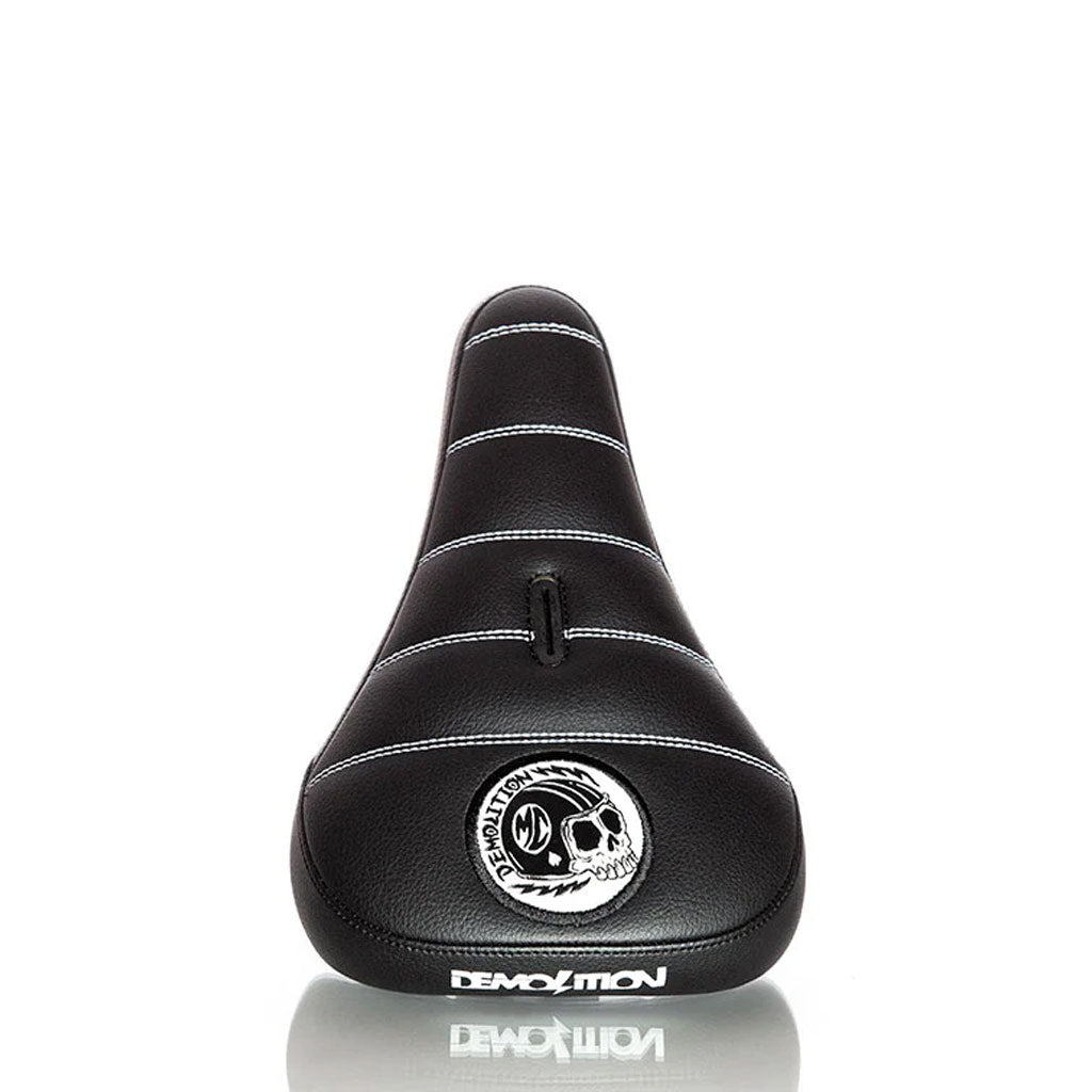 The Demolition Matt Cordova Seat (V2) is a black bicycle seat featuring a skull design, made from durable leatherette materials. It includes the word "Demolition" printed on it and offers Pivotal Fat Cap Padding for improved comfort during your rides.