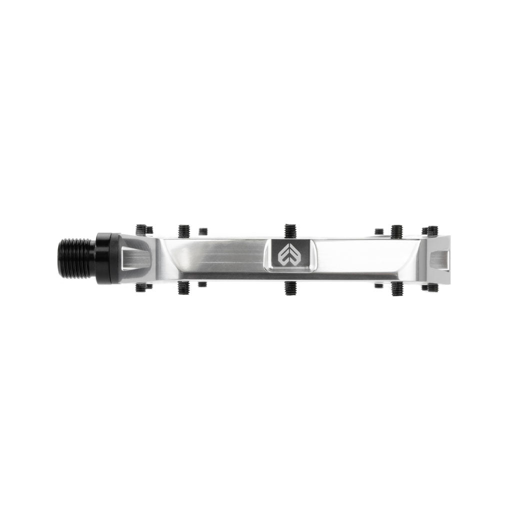 The Eclat Surge XL Pedal boasts a metallic rectangular design with an oversize platform area, complete with black screws and a black threaded spindle on one side. It features a logo with an upward-pointing arrow and incorporates a dual bearing/bushing spindle system for superior performance.