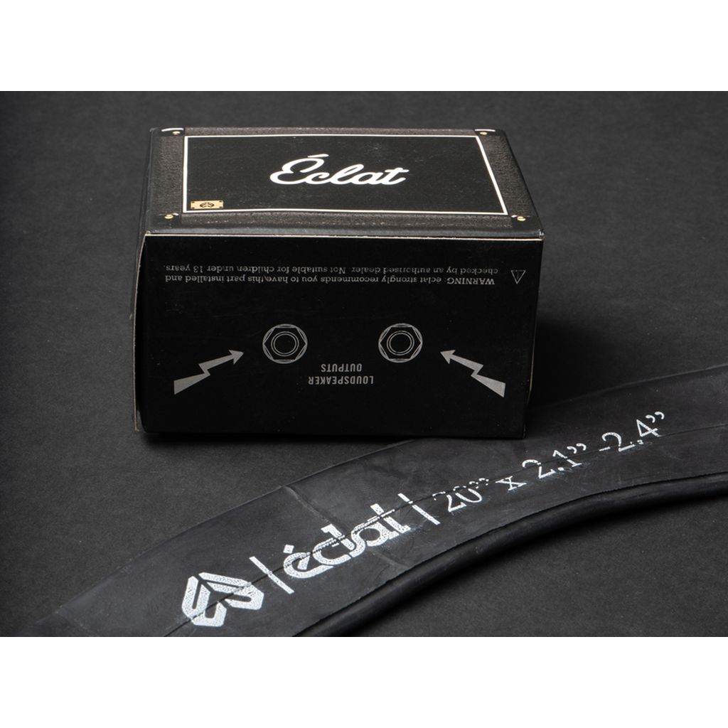 The Eclat Solo SV Tube, featuring a black inner tube with a Schrader valve, is presented in an Eclat branded box on a dark surface, making it ideal for wider tires.
