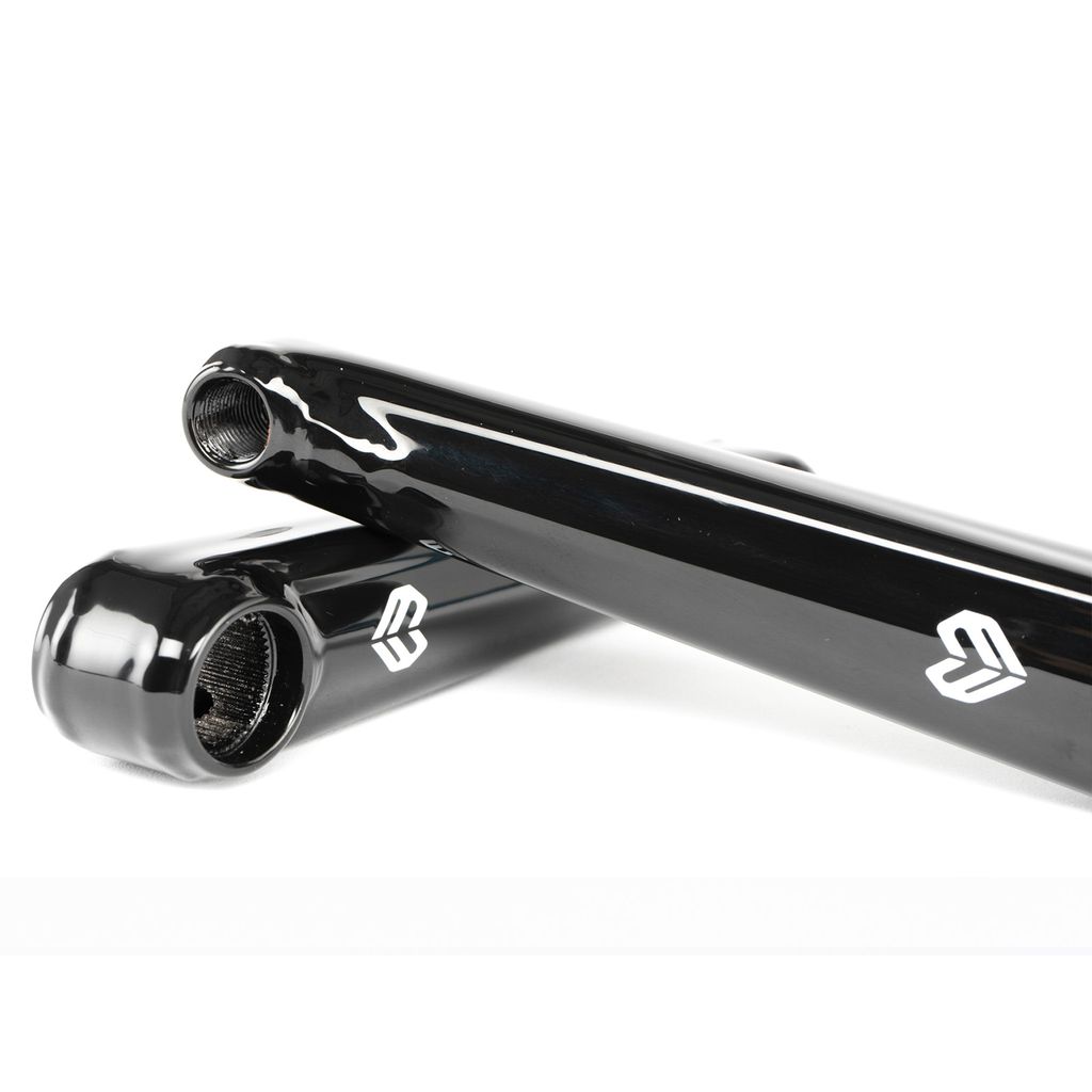 Close-up of two black, glossy metal tubes with threading on the ends and a white logo resembling a stylized "E" on their surfaces. Reminiscent of the sleek design found in BMX cranksets, these Eclat Tibia XLT Cranks are stacked at an angle against each other.