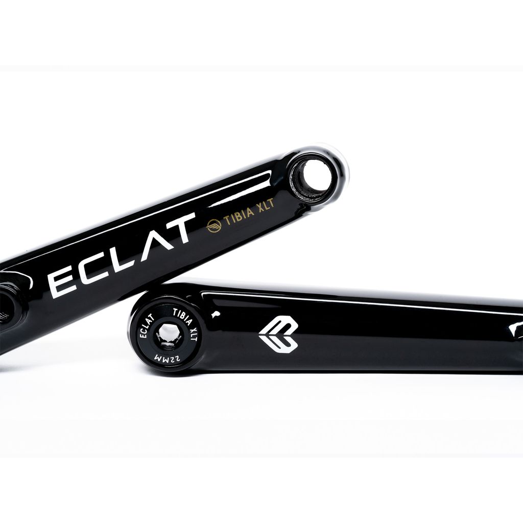 Close-up of two black bicycle crank arms with "Eclat Tibia XLT Cranks" branding. One displays "Eclat" and the other features a symbol and details. These BMX-ready, lightweight cranks are engineered for top performance.