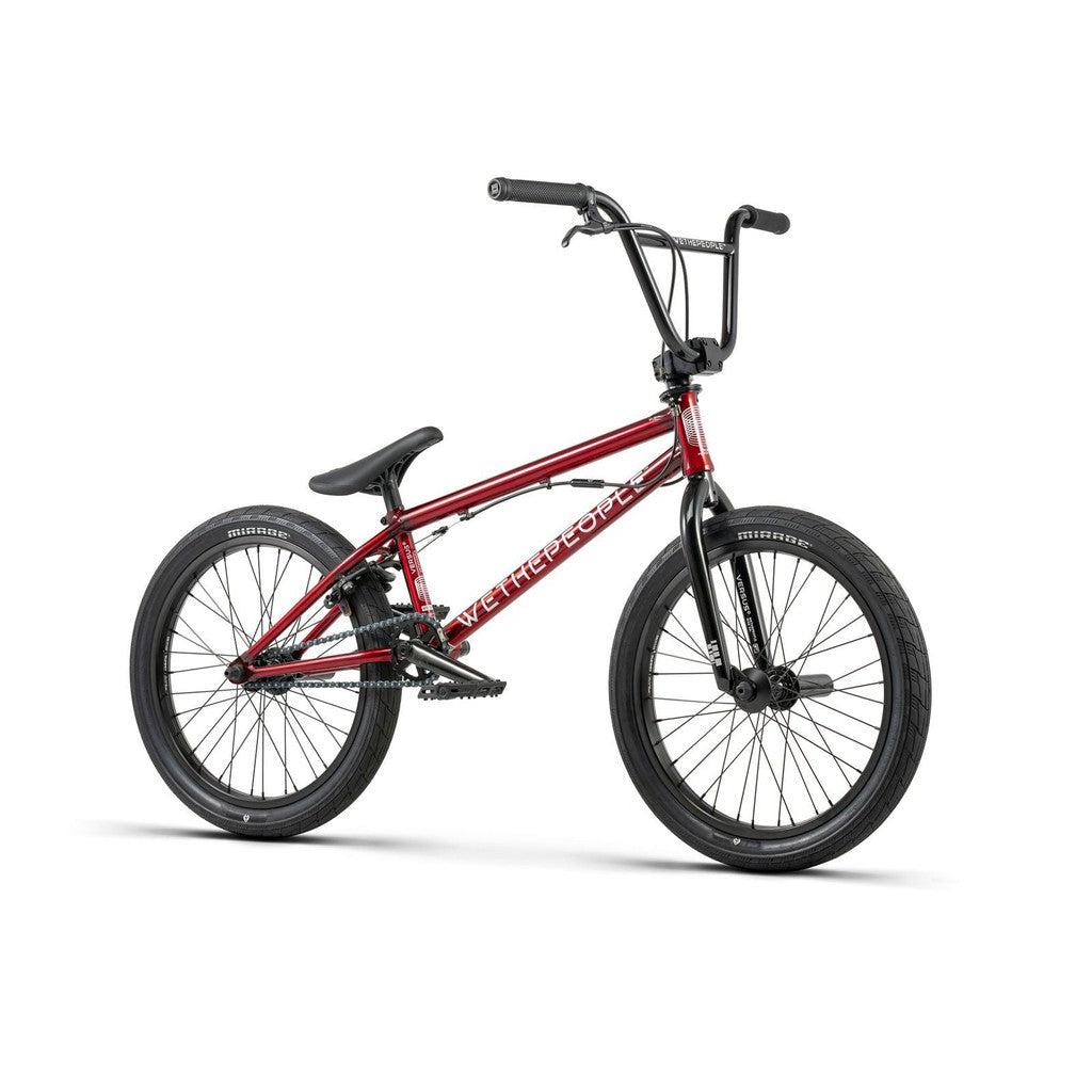 A red Wethepeople Versus 20 Inch Bike featuring a durable chromoly frame, black tires, and a black seat. "WE THE PEOPLE" is written on the frame, shown against a white background.