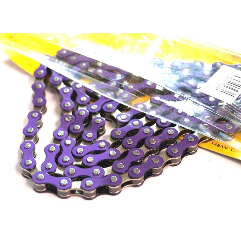 The YBN S-410 Full Link Chain, purple with 112 links for single speed bikes, is partially out of its yellow packaging, with a barcode visible at the top right.